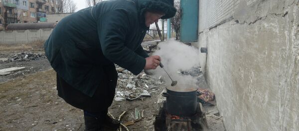 Жители города Дебальцево готовят еду на костре у подъезда пострадавшего в результате боевых действий жилого многоквартирного дома 1 марта 2015 - Sputnik Afrique