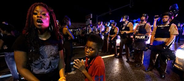 Amarion Allen, 11-years-old (C), and his mother Amima stand in front of a police line shortly before shots were fired in a police-officer involved shooting in Ferguson, Missouri August 9, 2015. - Sputnik Afrique