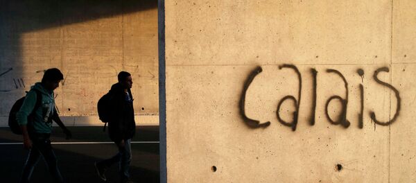 Migrants walk near a wall that is marked with the word Calais as they advance towards the Channel Tunnel access near Calais, France, July 31, 2015. - Sputnik Afrique