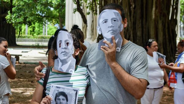 Cuban dissidents wear masks depicting US President Barack Obama as they protest against the reopening of the US embassy in the island, during a meeting of the Ladies in White human rights group in a park of Havana, on August 9, 2015. - Sputnik Afrique