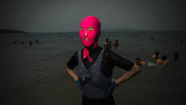 A woman wearing a facekini poses at the beach in Qingdao, eastern China's Shandong province on July 24, 2015. - Sputnik Afrique