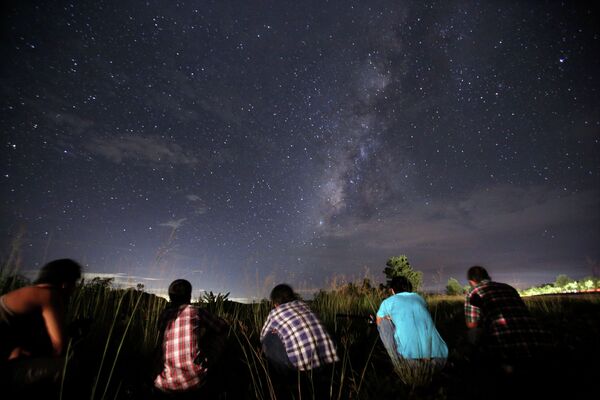 This long-exposure photograph taken on August 12, 2013 shows people watching for the Perseid meteor shower in the night sky near Yangon. - Sputnik Afrique