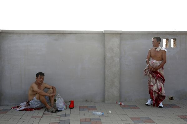 An injured man (R) looks on near the site of the explosions at the Binhai new district in Tianjin, China, August 13, 2015. - Sputnik Afrique