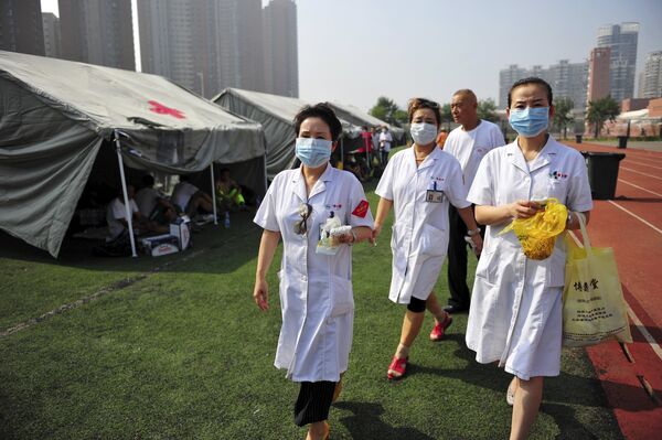Medical volunteers walk past tents set up at the playground of a primary school as temporary shelters for victims after explosions at Binhai new district in Tianjin, China, August 13, 2015. - Sputnik Afrique