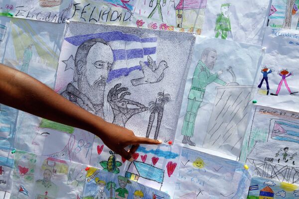 A youth points to children's drawings dedicated to Fidel Castro's 89th birthday inside the art studio of Alexis Leyva, known as Kcho in Havana, Cuba - Sputnik Afrique