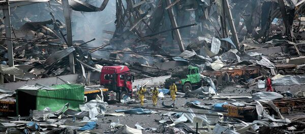 Rescue workers wearing chemical protective suits walk at the site of the explosions at the Binhai new district in Tianjin, China, August 14, 2015 - Sputnik Afrique