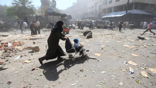 A woman pushes a baby stroller as she rushes away after what activists said were airstrikes by forces loyal to Syria's President Bashar al-Assad on a busy marketplace in the Douma neighborhood of Damascus, Syria August 12, 2015. - Sputnik Afrique