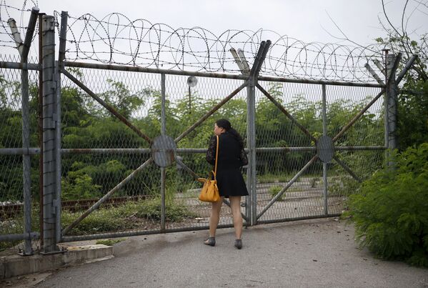 Китайская туристка смотрит сквозь забор вблизи демилитаризованной зоны, разделяющей Северную и Южную Корею - Sputnik Afrique