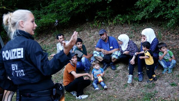 Une policière allemande se tient à côté de deux familles de réfugiés syriens près de Passau - Sputnik Afrique