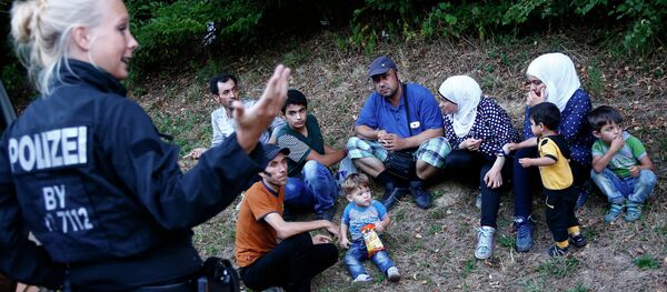 Une policière allemande se tient à côté de deux familles de réfugiés syriens près de Passau - Sputnik Afrique