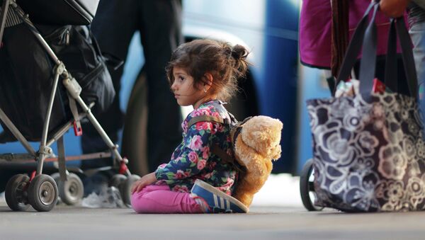 A migrant's girl waits to board a bus after arriving by train at Schoenefeld railway station, south of Berlin, Germany, September 13, 2015. - Sputnik Afrique