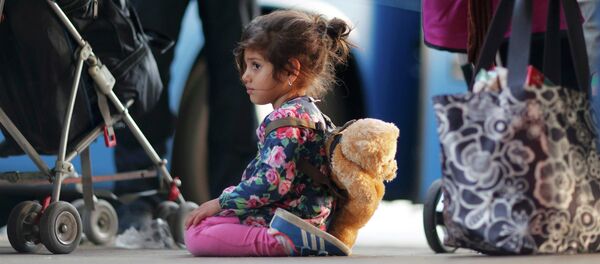 A migrant's girl waits to board a bus after arriving by train at Schoenefeld railway station, south of Berlin, Germany, September 13, 2015. - Sputnik Afrique
