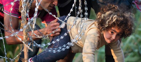 Une fille passe sous le fil de fer barbelé - Sputnik Afrique