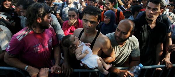 A migrant holds a baby as he waits to board a bus in Tovarnik, Croatia, September 17, 2015 - Sputnik Afrique