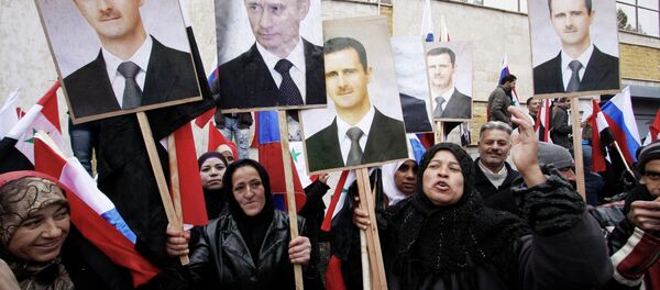 Manifestants avec les portraits du président Bachar el-Assad et président Vladimir Poutine, Damas. Archive photo - Sputnik Afrique