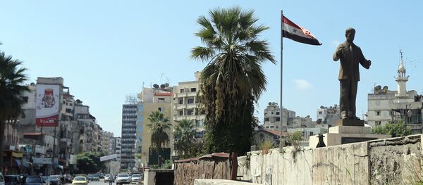A man rides his bike past a statue of late Syrian president Hafez al-Assad, father of current President Bashar al-Assad, in the Syrian coastal city of Latakia on September 24, 2015 - Sputnik Afrique
