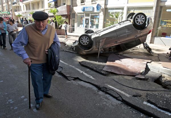A man walks past an overturned car in the street that was damaged in flooding caused by torrential rain in Cannes, France, October 4, 2015 - Sputnik Afrique