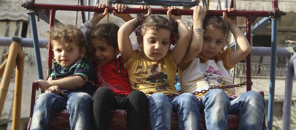 Children sit on a ferris wheel during Eid celebrations in Al-Fardous neighbourhood of Aleppo, Syria September 27, 2015. - Sputnik Afrique