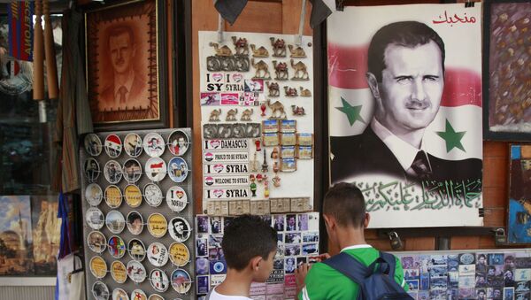 Des écoliers choisissent un souvenir dans un magasin où il y a le portrait de Bachar el-Assad avec la phrase On vous aime marqué dessus, Damas, Syrie - Sputnik Afrique