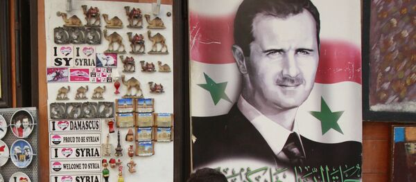 Des écoliers choisissent un souvenir dans un magasin où il y a le portrait de Bachar el-Assad avec la phrase On vous aime marqué dessus, Damas, Syrie - Sputnik Afrique