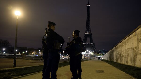 Police officers stand guard near the Eiffel Tower which has its lights turned off on November 14, 2015 following the deadly attacks in Paris. - Sputnik Afrique