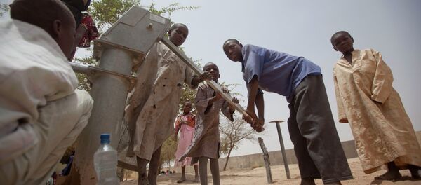 Des enfants pompent de l'eau pour boire dans un puits dans la cour d'un centre d'alimentation sans rendez-vous à Dibinindji, un village du désert dans la ceinture du Sahel au Tchad Des enfants pompent de l'eau pour boire dans un puits dans la cour d'un centre d'alimentation sans rendez-vous à Dibinindji, un village du désert dans la ceinture du Sahel au Tchad - Sputnik Afrique