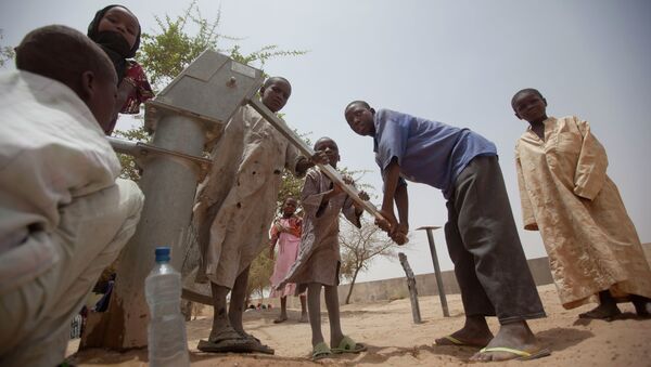 Des enfants pompent de l'eau pour boire dans un puits dans la cour d'un centre d'alimentation sans rendez-vous à Dibinindji, un village du désert dans la ceinture du Sahel au Tchad - Sputnik Afrique