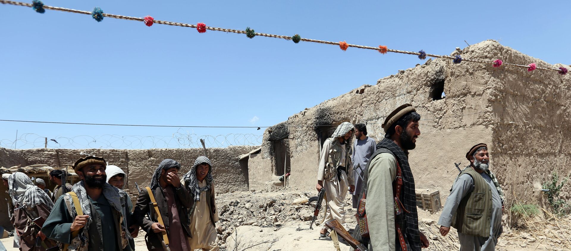 Sur cette photo de fichier du jeudi 21 mai 2015, des combattants d'une milice locale passent devant un bâtiment incendié par des combattants talibans dans le village de Talawka, dans la province de Kunduz, au nord de Kaboul, en Afghanistan. - Sputnik Afrique, 1920, 19.03.2021