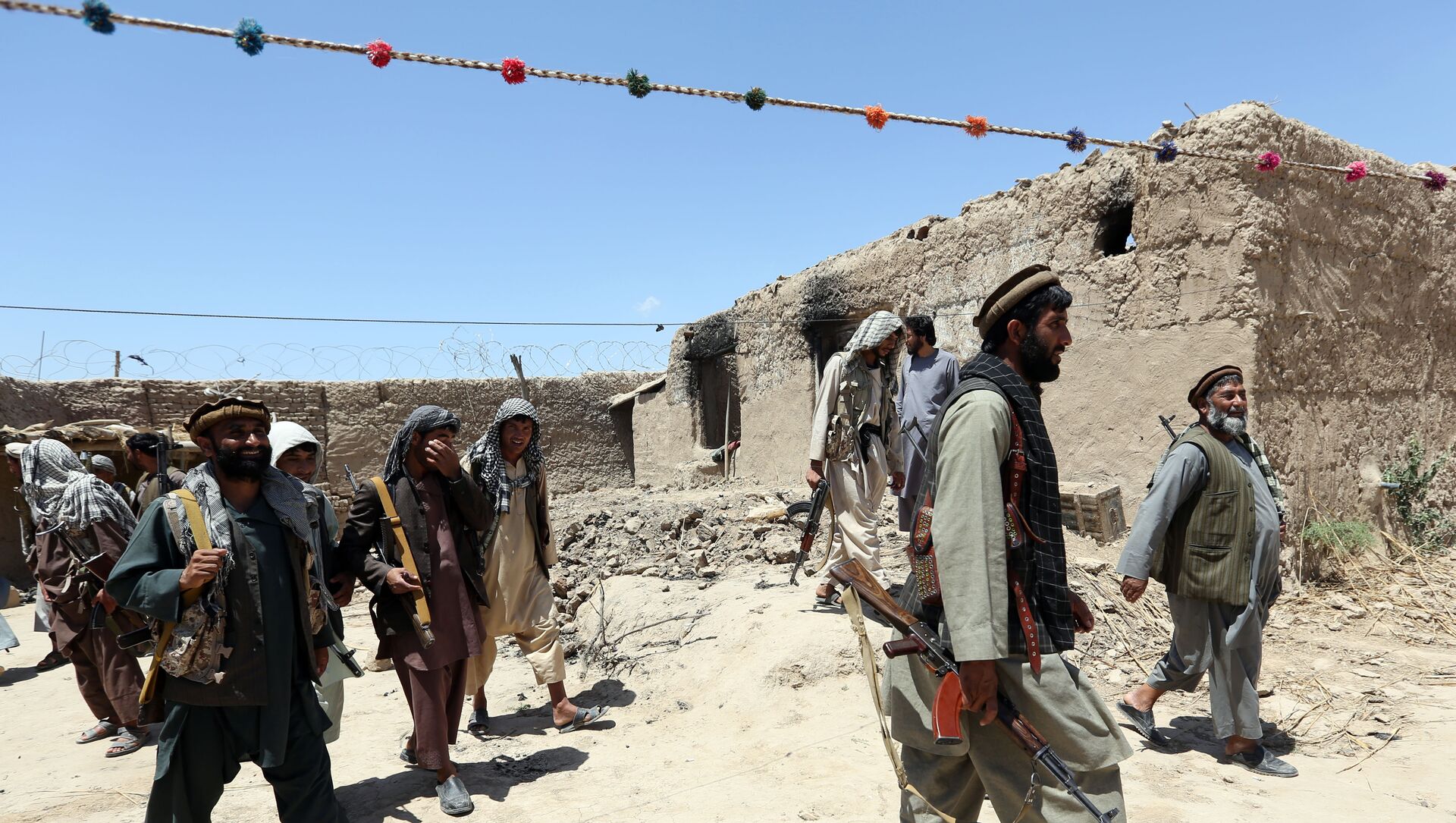 Sur cette photo de fichier du jeudi 21 mai 2015, des combattants d'une milice locale passent devant un bâtiment incendié par des combattants talibans dans le village de Talawka, dans la province de Kunduz, au nord de Kaboul, en Afghanistan. - Sputnik Afrique, 1920, 19.03.2021