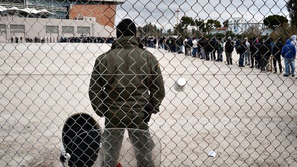 A riot policeman stands guard at a temporary housing facility for migrants nad refugees located in a former Olympic hall in Faliro suburb of Athens on December 11, 2015. - Sputnik Afrique