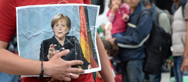 Un migrant tient le portrait d'Angela Merkel Un migrant tient le portrait d'Angela Merkel - Sputnik Afrique