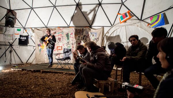 migrants écoutent un guitariste dans un théâtre improvisée, Calais - Sputnik Afrique