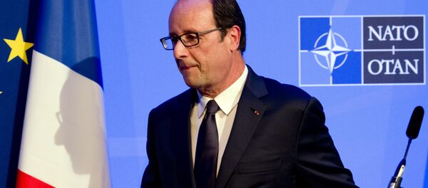 Une ombre du président François Hollande de la France est jeté sur un drapeau comme il laisse une conférence de presse sur la deuxième journée du sommet de l'OTAN 2014 au Celtic Manor Resort à Newport, au Pays de Galles du Sud, le 5 Septembre, 2014 - Sputnik Afrique
