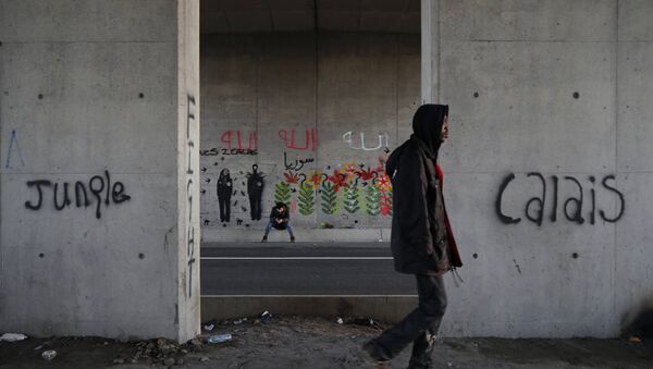 Les immigrants font leur chemin le long d'une route près de graffiti avec les mots Jungle, Calais à Calais, France, le 20 Octobre 2015. - Sputnik Afrique