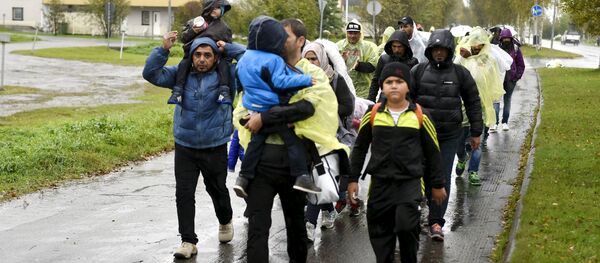 Refugees walk through the pouring rain from a public transport centre to the Lappia-building refugee reception centre in Tornio, northwestern Finland, on September 2015 - Sputnik Afrique