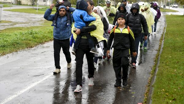 Refugees walk through the pouring rain from a public transport centre to the Lappia-building refugee reception centre in Tornio, northwestern Finland, on September 2015 - Sputnik Afrique
