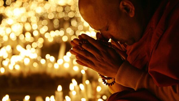 Surrounded by some thousands of candles, Sri Lankan Buddhist monk Pananwela Gnanalankara prays for the earthquake victims at a park in Itami, western Japan, 16 January 2005, one day before the 10th anniversary of the massive earthquake which killed more than 6,400 people. - Sputnik Afrique