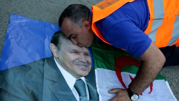A supporter of Algerian President Abdelaziz Bouteflika kisses his picture as he celebrates in Algiers on April 18, 2014 after Bouteflika won a fourth term with 81,53% of the votes. - Sputnik Afrique