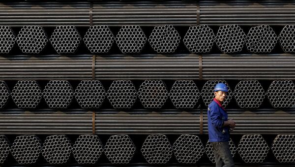 A worker walks past a pile of steel pipe products at the yard of Youfa steel pipe plant in Tangshan in China's Hebei Province in this November 3, 2015 file photo. - Sputnik Afrique