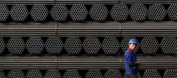 A worker walks past a pile of steel pipe products at the yard of Youfa steel pipe plant in Tangshan in China's Hebei Province in this November 3, 2015 file photo. - Sputnik Afrique