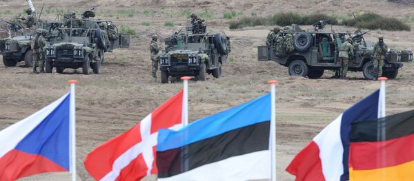 Les drapeaux vague en face de soldats qui prennent des positions avec leurs véhicules blindés pendant l'exercice militaire de l'Otan près Swietoszow Zagan, Pologne - Sputnik Afrique