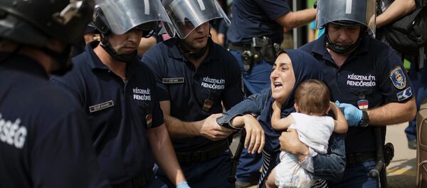 A migrant family is arrested by local police after their local train coming from Budapest and heading to the Austrian border has been stopped in Bicske, west of the Hungarian capital on September 3, 2015. - Sputnik Afrique