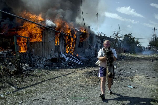 Sur la photo : un habitant local sauve un chien d'incendie dans une maison, endommagée au cours d'une attaque aérienne par les forces armées ukrainiennes contre le village de Louganskaïa. - Sputnik Afrique