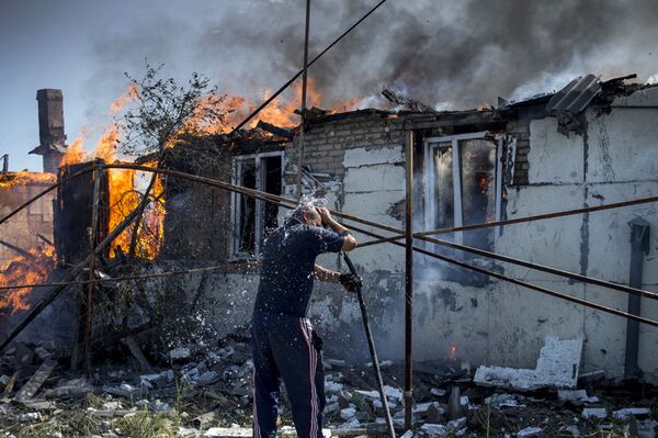 Sur la photo : un habitant local éteigne un incendie dans une des maisons dans le village de Louganskaïa subi des frappes aériennes par les forces armées de l'Ukraine. - Sputnik Afrique
