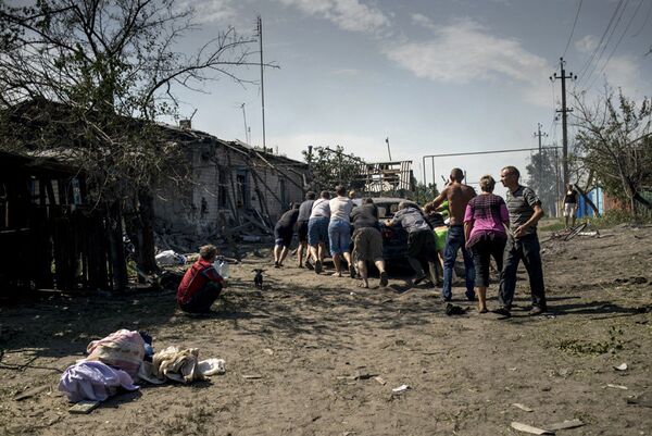 Sur la photo : les habitants locaux essayent de déplacer une voiture à partir d'une maison en feu dans le village de Louganskaïa qui a subi des frappes aériennes par les forces armées ukrainiennes. - Sputnik Afrique