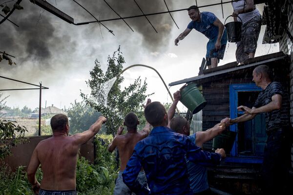 Sur la photo : les habitants luttent contre un incendie dans une des maisons dans le village de Louganskaïa subi des frappes aériennes par les forces armées de l'Ukraine. - Sputnik Afrique
