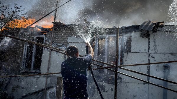 Sur la photo : un habitant local lutte contre le feu dans une des maisons du village de Louganskaïa subi des frappes aériennes par les forces armées ukrainiennes. - Sputnik Afrique
