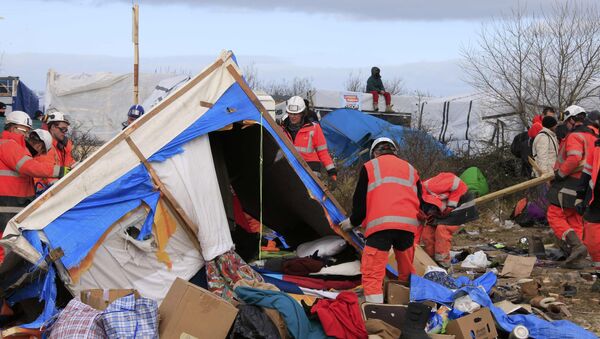 A migrant sits on his makeshift shelter as workmen start to dismantle a section of the camp for migrants called the jungle, in Calais, northern France, February 29, 2016. - Sputnik Afrique