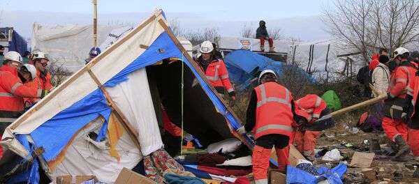 A migrant sits on his makeshift shelter as workmen start to dismantle a section of the camp for migrants called the jungle, in Calais, northern France, February 29, 2016. - Sputnik Afrique