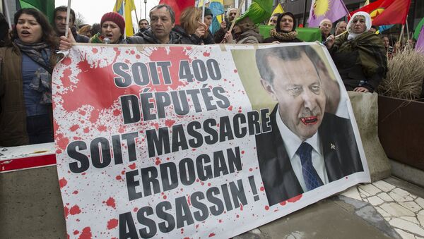 Kurdish people display a picture of Turkish President Tayyip Erdogan during a protest outside an EU-Turkey summit as the bloc is looking to Ankara to help it curb the influx of refugees and migrants flowing into Europe, in Brussels March 7, 2016 - Sputnik Afrique